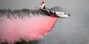 Ein Tankflugzeug der Feuerwehr wirf Löschmittel über einem Waldbrand in Australien ab.