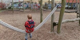 Ein Kind sitzt auf einem Seil auf einem Spielplatz