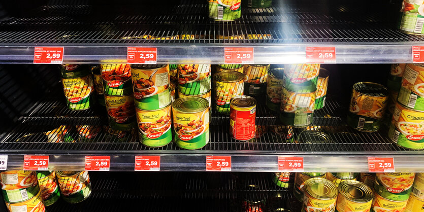 Fast leergekauftes Regal mit Dosen in einem Supermarkt.