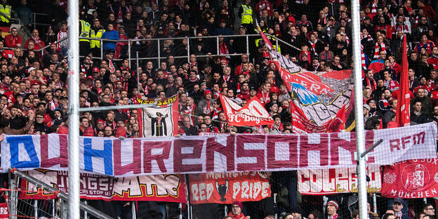 Im Stadion halten Fans ein Banner mit der Aufschrift "Du Hurensohn"