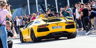 Ein Lamborghini wird von Menschen bei einem Autotreffen angeschaut.