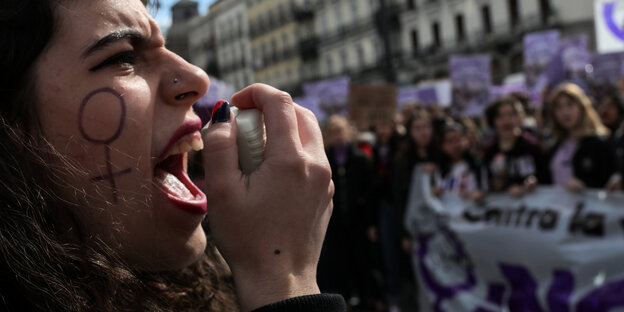 Eine Frau schreit auf einer Demonstration in ein Mikrofon.