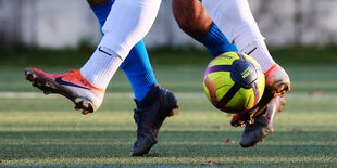 Füße von Fußballspielern mit Ball.