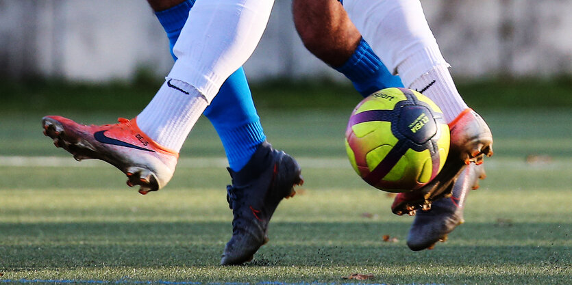 Füße von Fußballspielern mit Ball.