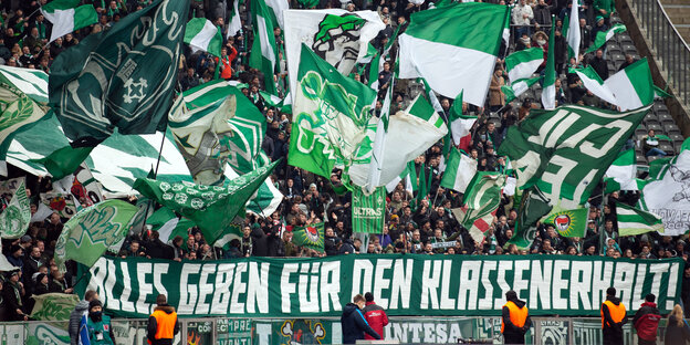Werder gegen Hertha im Olympiastadion: Gästefans feiern. Auf einem Banner steht: Alles geben für den Klassenerhalt!