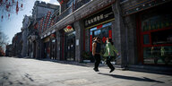 Zwei chinesische Mädchen springen auf einer menschenleeren Straße in Peking Seil