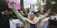 Eine Frau mit Kopftuch und erhobenen Armen protestiert vor einem Plakat mit dem Bild des indischen Ministerpräsidenten Modi gegen die Gewalt in Neu-Delhi