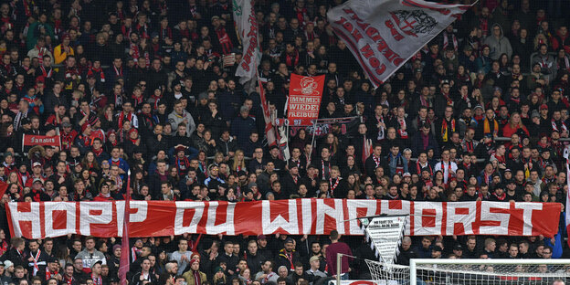 Freiburger Fans halten Spruchband hoch, auf dem steht „Hopp, Du Windhorst“