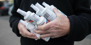 Ein Mann hält sechs Flaschen Desinfektionsmittel in den Händen