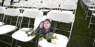 weiße Stühle, auf einem Stuhl liegt ein Foto, das ein junges Paar zeigt und zwei weiße Rosen