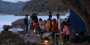 Kinder und Erwachsene an einem Feuer am Meer