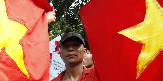 Nguyen Huy Kham zwischen vietnamesischen Flaggen
