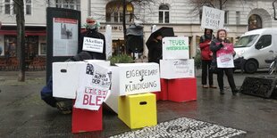 Aktivist*innen mit Plakaten in der Hand – sie protestieren gegen Immobilienunternehmen am George-Grosz-Platz