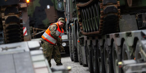 Soldat in Warnweste und Panzer auf Lastwagen