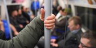 Eine Hand hält die Haltestange in einem Londoner Bus