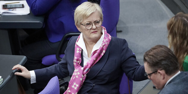 Renate Künast sitzt auf einem Drehstuhl im Bundestag und dreht sich zu ihren Fraktionskolleginnen und Fraktionskollegen um