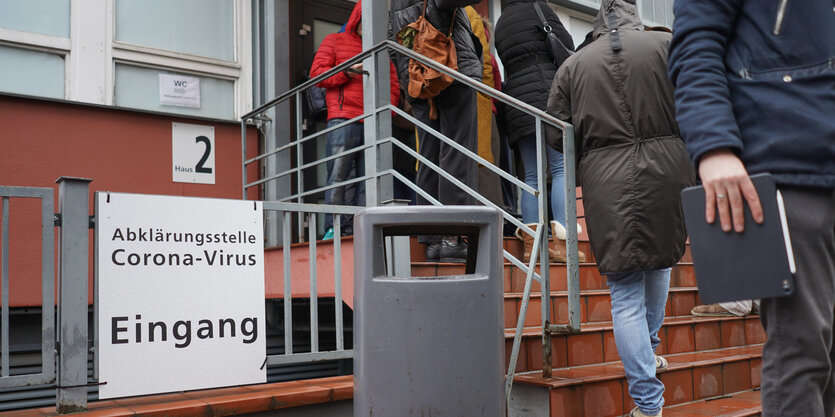 Menschen stehen auf einer Treppe vor einem Krankenhaus an