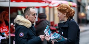 Eine Frau redet mit einem Mann und zeigt ihm Wahlkampfbroschüren