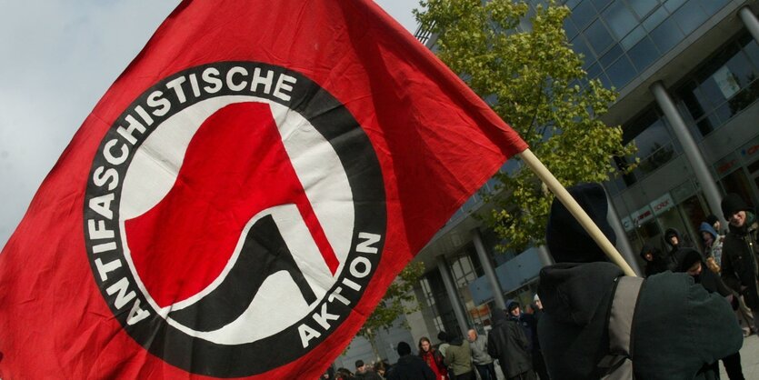 Ein Mann hält eine Flagge auf der steht "Antifaschistische Aktion"