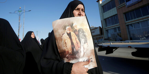 Eine Frau hält ein Plakat mit Fotos von Qassem Suleimani und Mahdi al-Muhandis