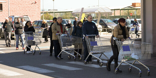 Italien, Rom: Kunden stehen vor einem Supermarkt an und halten dabei aufgrund von Ansteckungsgefahr einen Sicherheitsabstand ein.