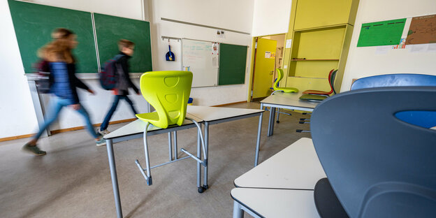 2 Kinder eilen durch ein leeres Klassenzimmer