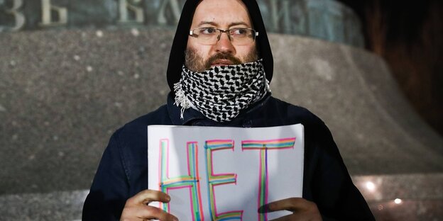 Ein mann hält ein Schild auf das das Wort "Nein" auf russisch zu lesen ist