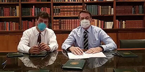 Zwei Männer mit Atemschutzmasken vor einem Bücherregal