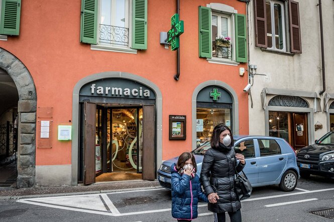 Eine Frau und ein Kind mit Schutzmasken vor einer Apotheke