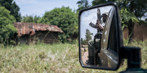 Ein Ranger sitzt mit einer Waffe auf einem Auto. Man sieht ihn im Rückspiegel