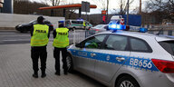 Zwei polnische Polizisten stehen neben ihrem Einsatzwagen am deutsch-polnischen Grenzübergang bei Görlitz