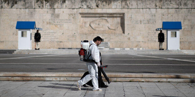 zwei Reinigungskräfte versprühen vor dem Parlament in Athen Desinfektionsmittel
