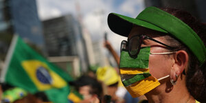 Eine demonstrantin in Sao Paulo trägt eine Maske