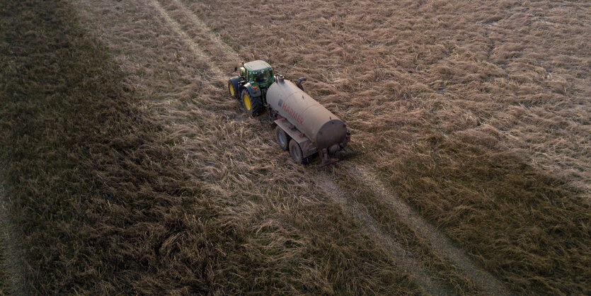 Ein Landwirt verteilt mit seinem Traktor Gülle auf einem Feld