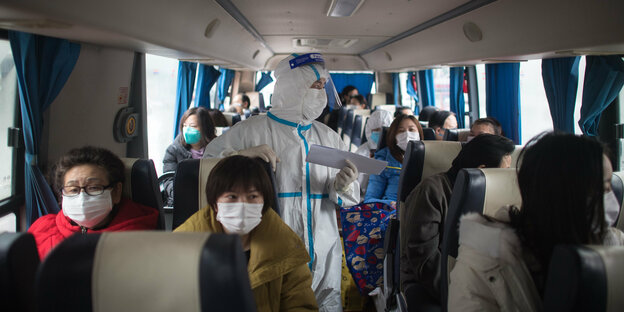 Menschen mit Mundschutz in einem Bus
