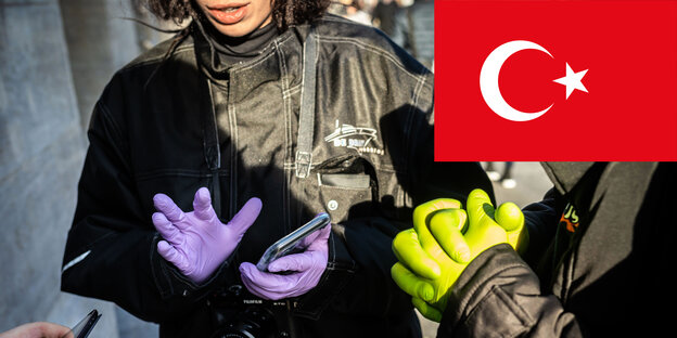 Corona-Infos auf Türkisch - Menschen mit Schutzhandschuhen vor einem Apple Store