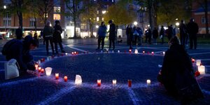 Menschen entzünden Kerzen auf dem Carlebach-Platz in Hamburg.