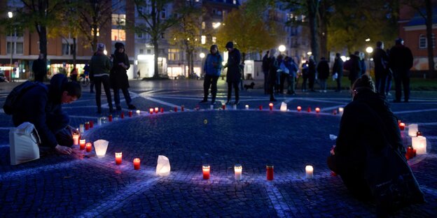 Menschen entzünden Kerzen auf dem Carlebach-Platz in Hamburg.