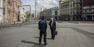ein Polizist und ein Passant unterhalten sich azf einer Straße