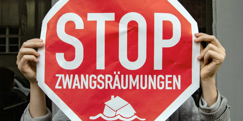 Ein mensch hält ein Stopschild gegen Zwangsräumungen in die Höhe