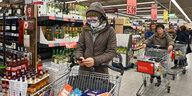 Eine Frau kauft mit Atemschutzmaske und Schutzbrille im Supermarkt ein.