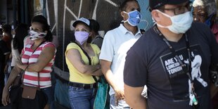 Menschen stehen in einer Schlange vor einem Supermarkt in Caracas in Venezuela.