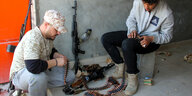 Bewaffnete Kämpfer in Libyen basteln an ihren Waffen.