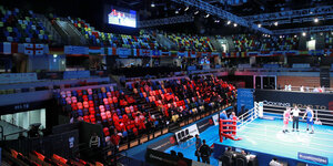 Eine Halle mit Boxring und fast leerer Zuschauertribüne