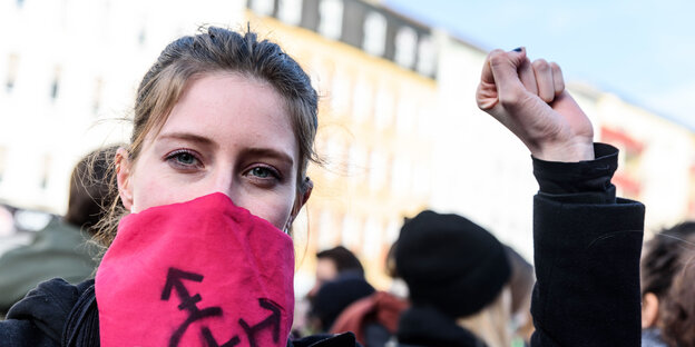 Eine vermummte Demonstrantin am Frauentag rekt die linke Faust.