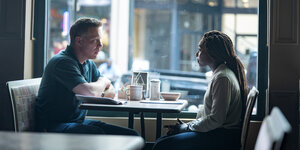Eine Frau und ein Mann sitzen sich im Café gegenüber.