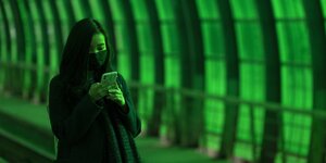 Frau mit Smartphone in einem grünen Tunnel