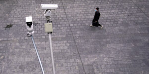 Ueberwachungskamera auf einem leeren Platz, Mensch mit Maske