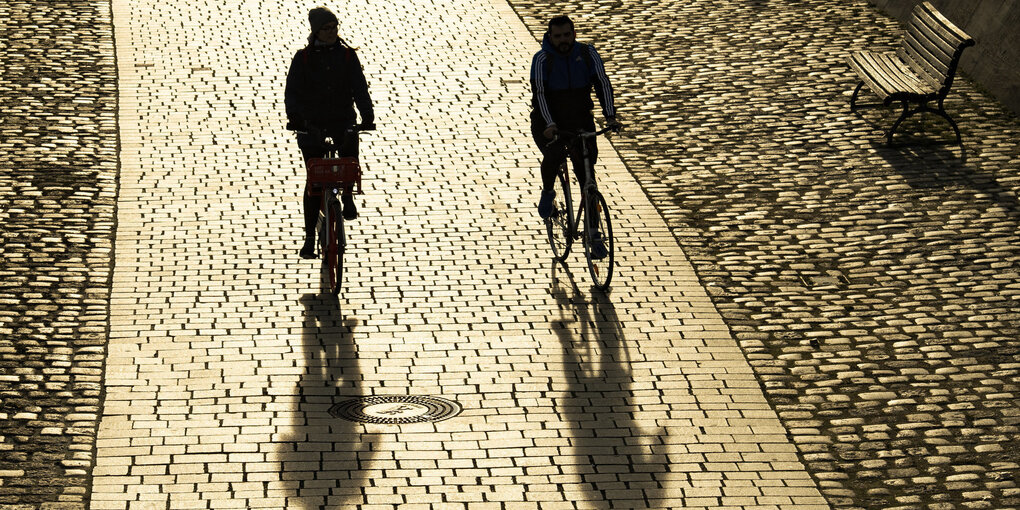 Zwei RadfahrerInnen im Gegenlicht.