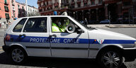 Ein Polizeifahrzeug mit Lautsprecher im Fenster fährt durch eine Starße in Neapel.